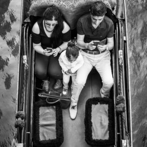 Noir et blanc : famille en gondole à Venise, utilisant leurs téléphones. #Venise #Gondole