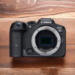 Appareil photo Canon EOS R7 noir sur bois. Boîtier hybride, monture RF, capteur APS-C.