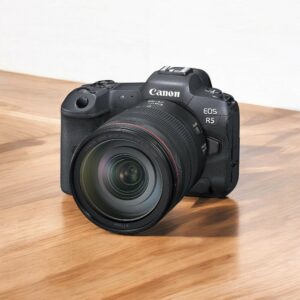 Appareil photo Canon EOS R5 avec objectif sur table en bois. Photographie numérique professionnelle.