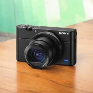 Appareil photo numérique Sony noir avec objectif Zeiss sur table en bois.