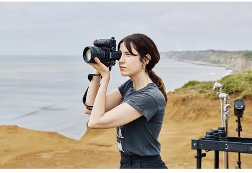 Photographe utilisant un appareil photo Sony A1 II sur une falaise avec vue sur l'océan. 