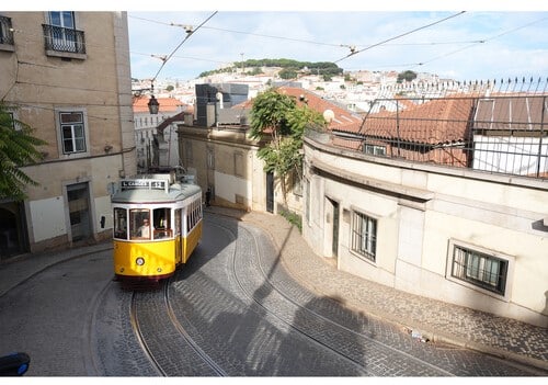 Tram jaune de Lisbonne sur une rue pavée, avec le Sony A7 V capturant l'instant. Transport urbain pittoresque.
