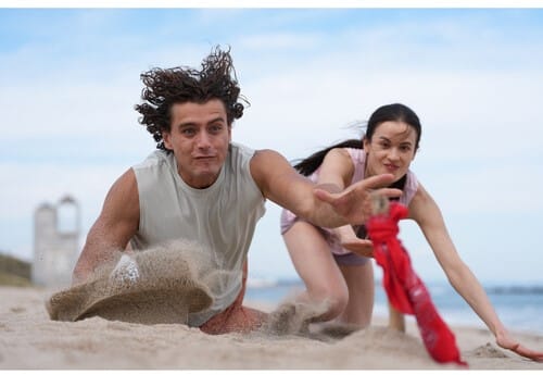 Photo Sony A7 V: Un homme et une femme jouent au jeu du foulard sur la plage, capturant l'esprit de compétition et de plaisir.