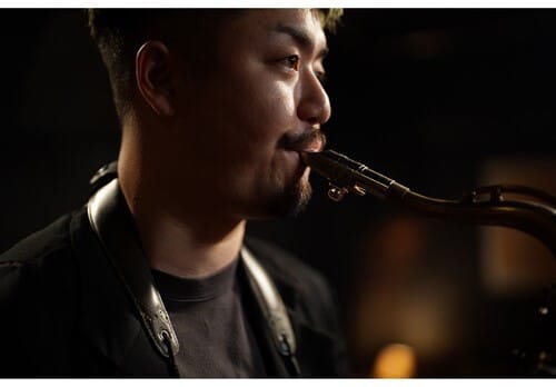 Homme jouant du saxophone avec un Sony A7 V. Musicien de jazz avec un instrument à vent. Performance musicale.