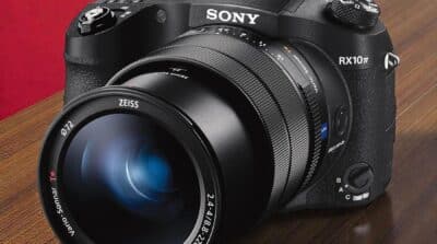 Sony RX10 IV vue de face sur table en bois. Appareil photo bridge haut de gamme avec objectif Zeiss Vario-Sonnar T*.