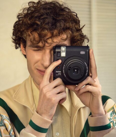 Photographe utilisant un Instax Mini 99, le meilleur appareil photo instantané en 2026, pour capturer des souvenirs.