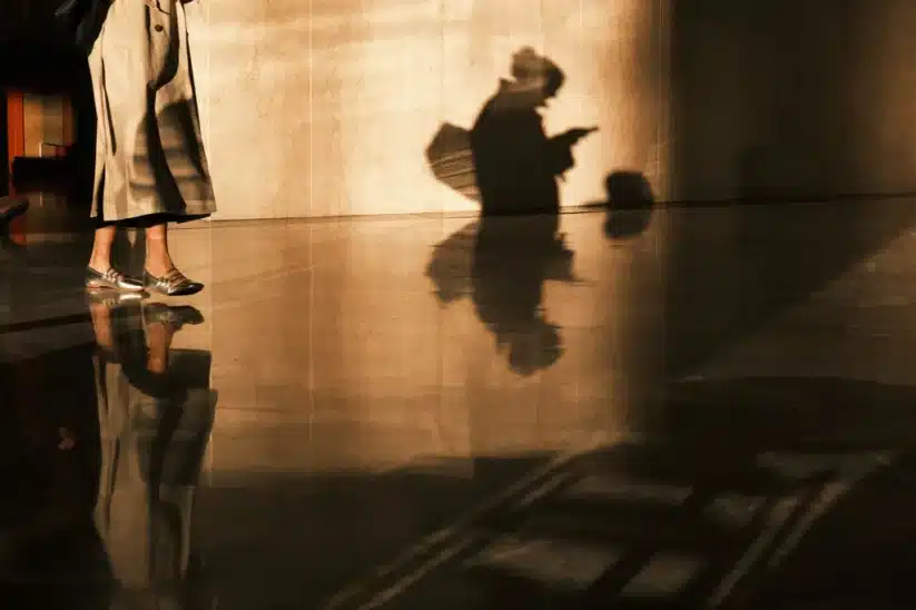 Ombres et reflets artistiques capturées avec le Fujifilm X-E5: une silhouette mystérieuse et des chaussures élégantes.