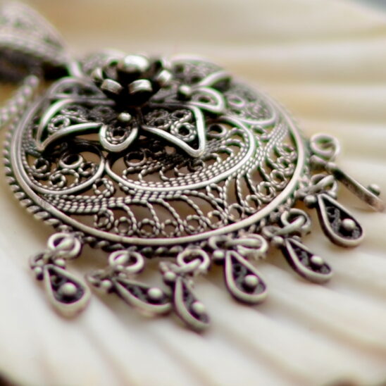 Bijou de filigrane argenté complexe. Pendentif détaillé avec des ornements délicats. Aberration chromatique.