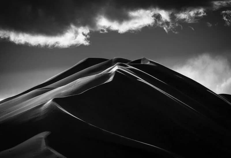 Photo noir et blanc de dunes de sable, choix appareil photo hybride ou reflex en 2026, paysages désertiques.