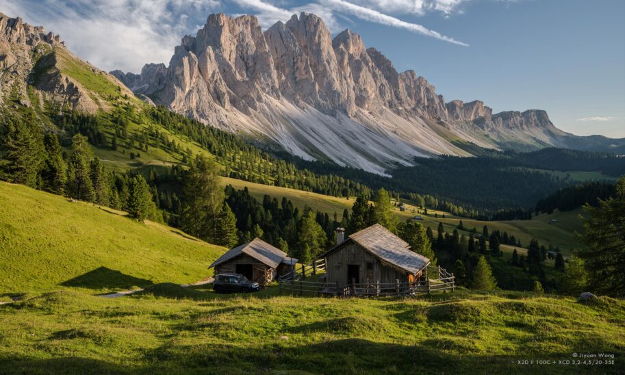 Paysage moyen format Hasselblad X2D II 100C&nbsp;: cabanes en bois, montagne rocheuse et prairie verdoyante en Italie.