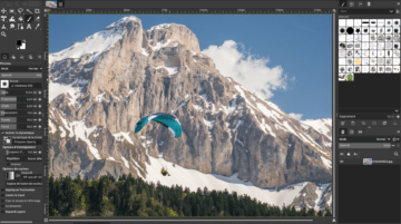 GIMP logiciel photo gratuit: Interface GIMP avec paysage montagneux et parapente en retouche.