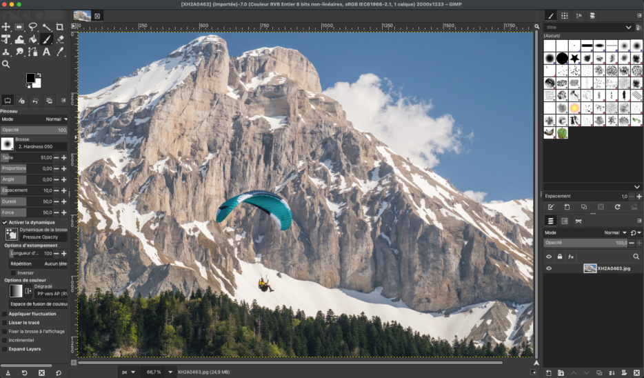GIMP logiciel photo gratuit: Interface GIMP avec paysage montagneux et parapente en retouche.