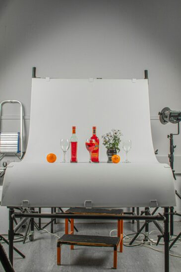 Studio professionnel de photographie culinaire avec table de prise de vue, fond blanc et bouteilles colorées