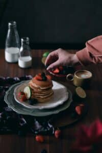 Photographie culinaire moody de pancakes aux fruits rouges et mûres. Guide pour sublimer vos plats.
