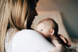 Photo nouveau-né : Bébé blotti contre l'épaule de sa maman. Guide pour réussir vos clichés de nouveau-nés.