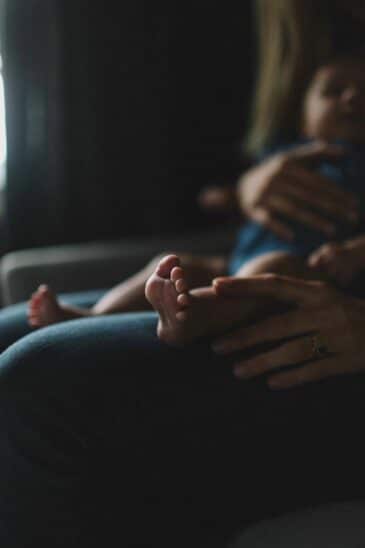 Photo nouveau-né&nbsp;: pieds de bébé dans les bras de maman, clair-obscur. Guide pour réussir vos clichés de nouveau-né.