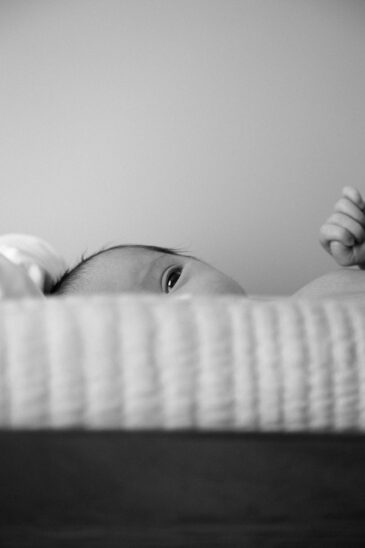 Photo nouveau-né en noir et blanc, regard du bébé dans son berceau. Guide pour réussir vos clichés de bébé. 