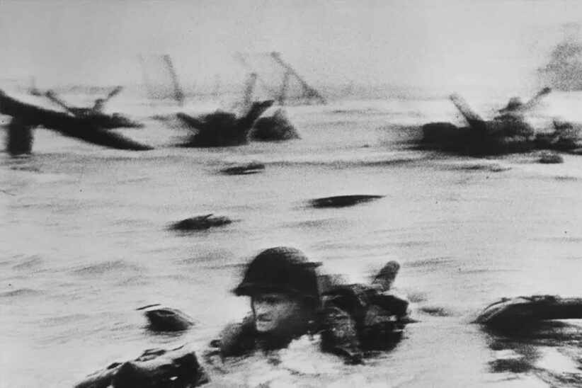 Robert Capa&nbsp;: Débarquement en Normandie, photo de guerre iconique. Soldat dans eau, obstacles. Un des photographes les plus connus.