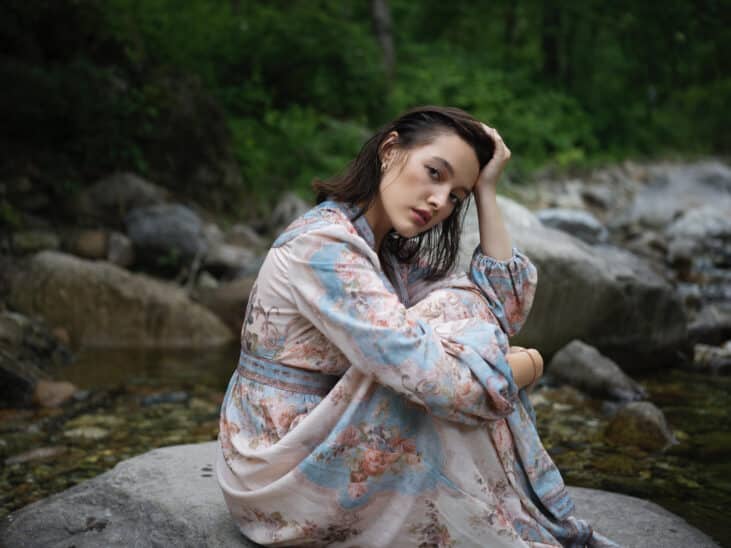 Portrait d'une femme Hasselblad X2D II 100C en robe fleurie, assise sur un rocher. Photographie moyen format.