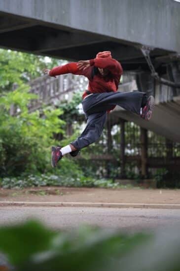 Danseur en plein saut sous un pont, figé en l'air au-dessus d'une allée