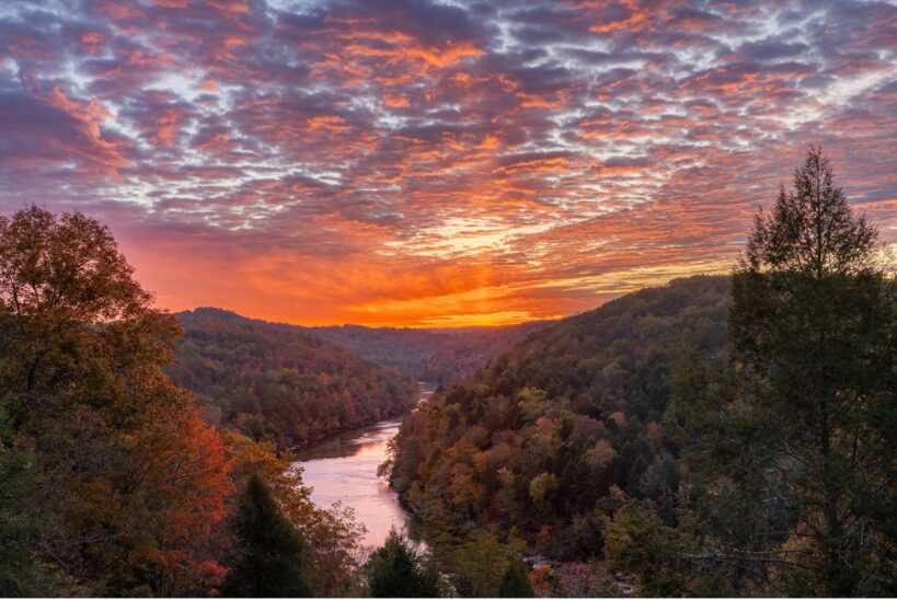 Ciel flamboyant au coucher du soleil au-dessus d'une vallée boisée et d'une rivière