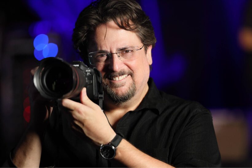 Photographe souriant tenant le Canon EOS R6 Mark III équipé d'un objectif lumineux