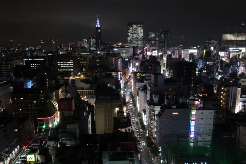 Vue nocturne d'une grande ville illuminée, avec une tour éclairée à l'horizon
