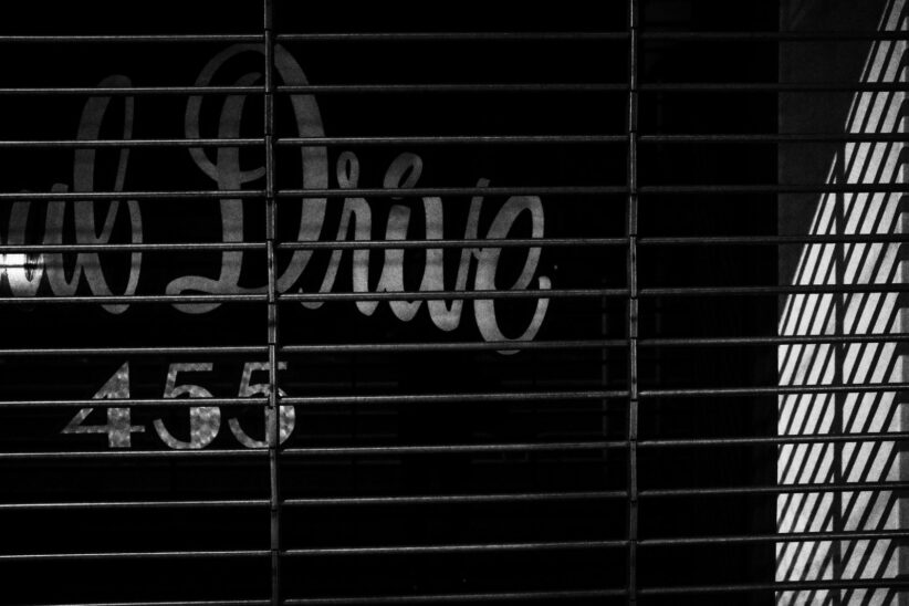 Rideau métallique devant une enseigne peinte à la main et le numéro 455, en noir et blanc contrasté