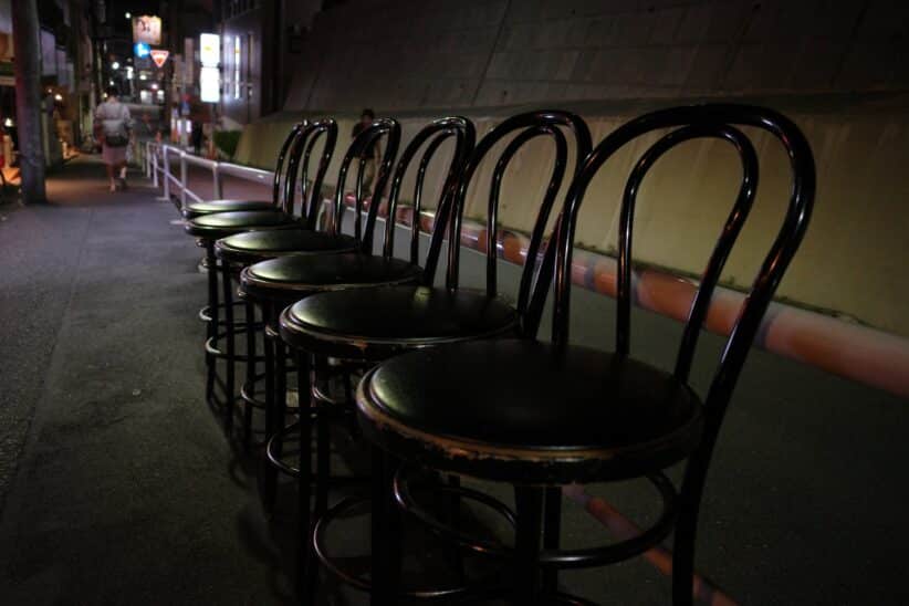 Rangée de tabourets de bar alignés dans une ruelle sombre, la nuit
