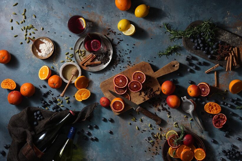 Nature morte d'agrumes coupés, d'épices et de petits bols sur un plan de travail bleu sombre